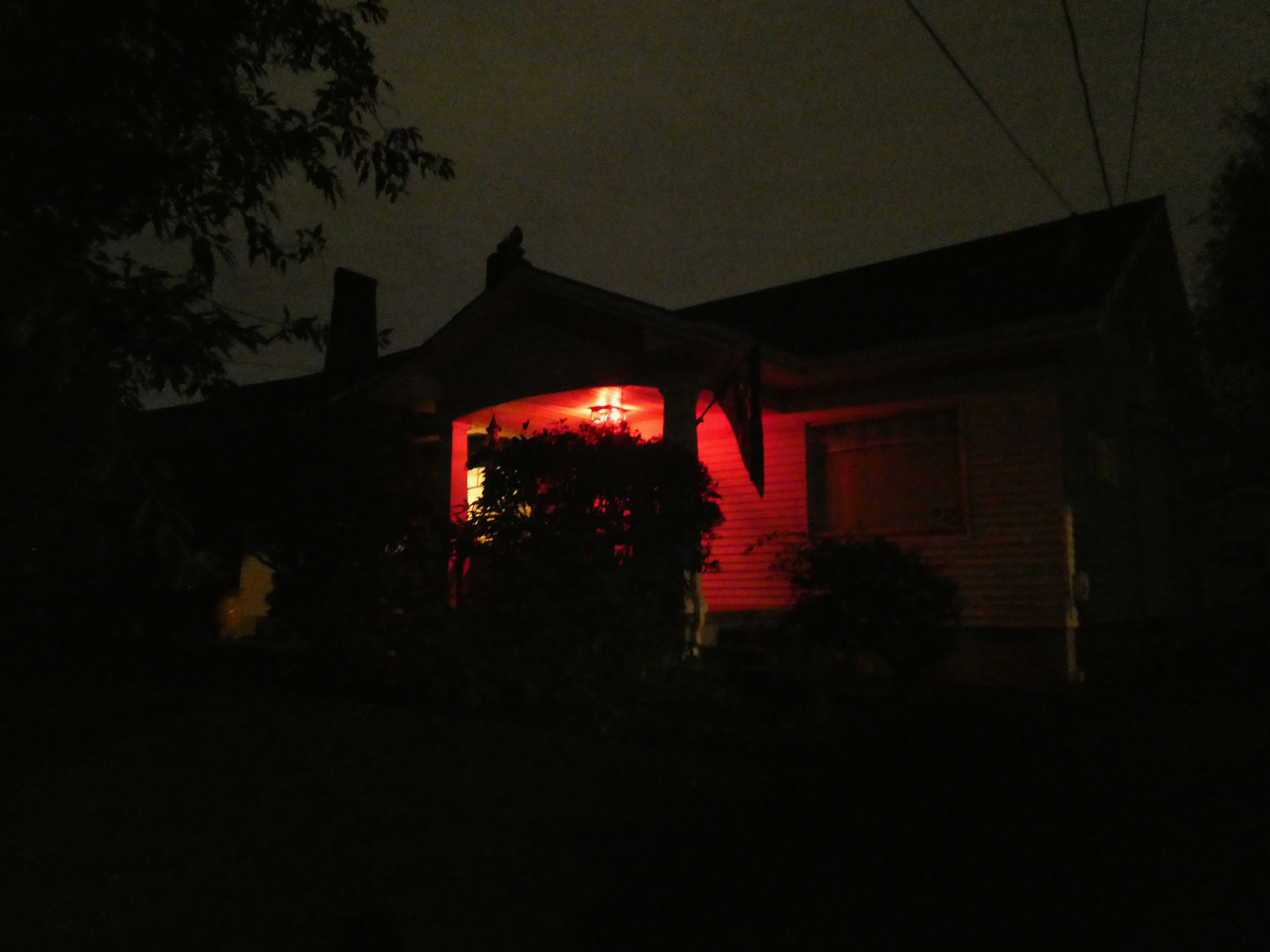 A house in the dark lit only by a red porch light.